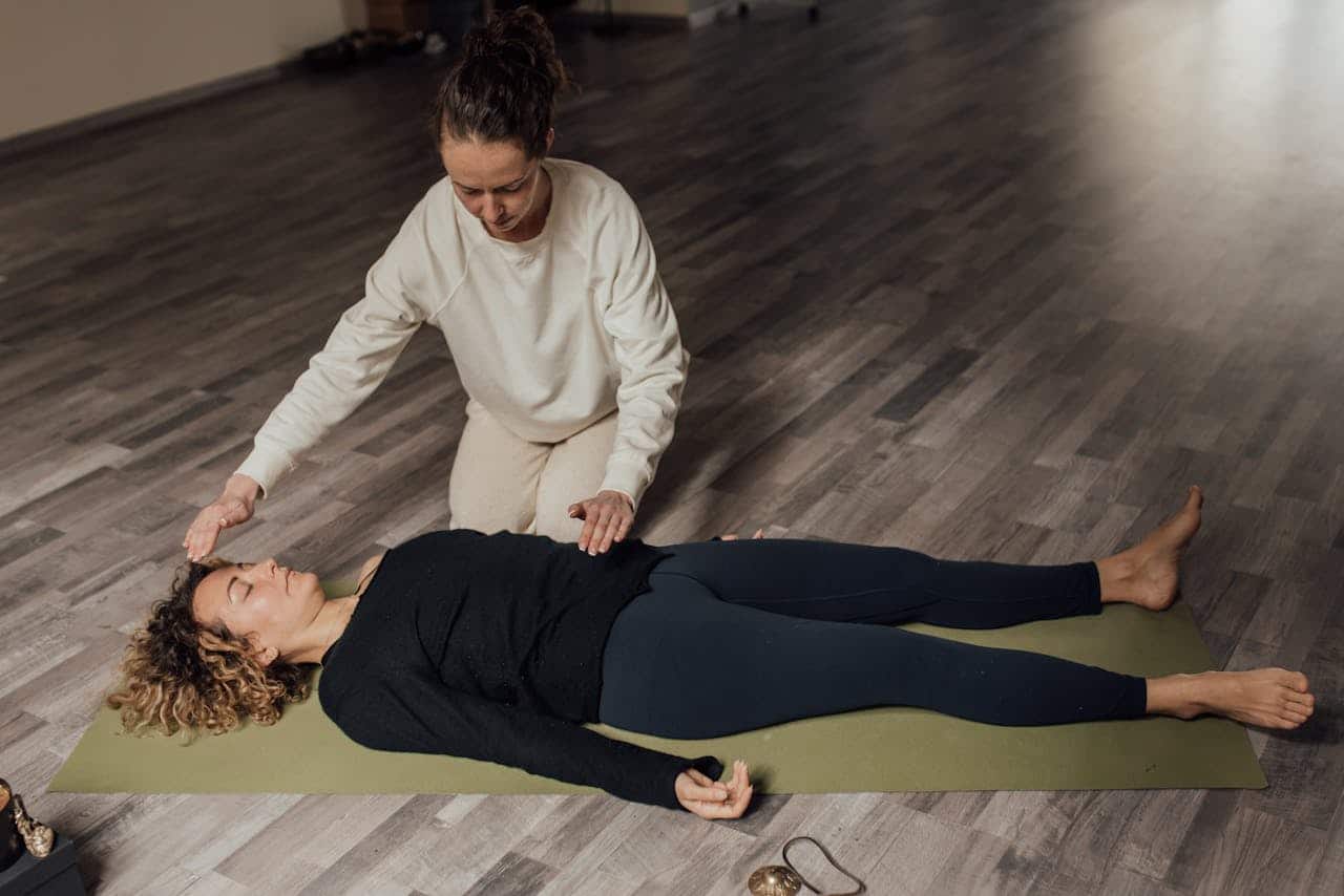 Two women involved in a serene meditation and healing practice session indoors.